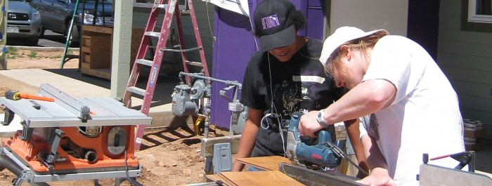 Two people working with a saw on a construction site. 