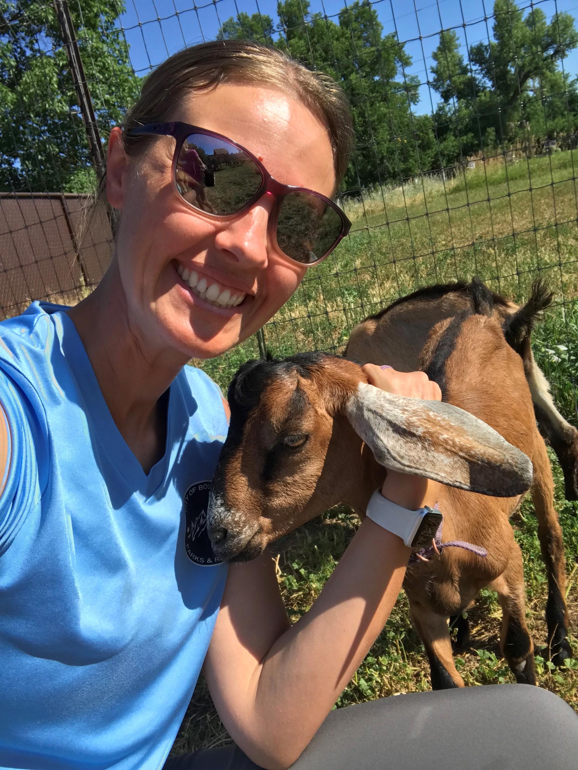 Molly smiles while petting a goat.