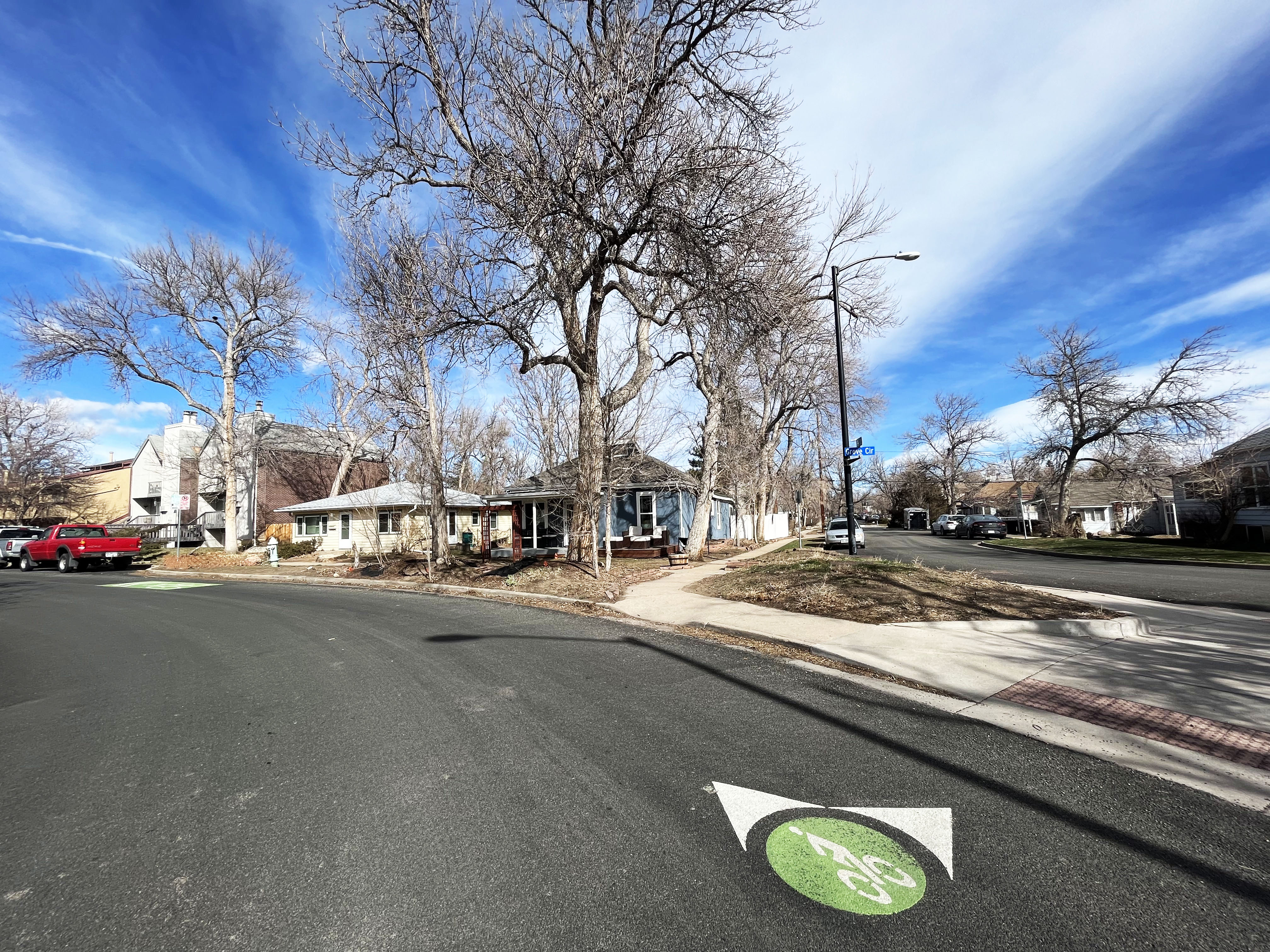 a green wayfinding symbol on the road with green paint, a white bicycle symbol and white arrows