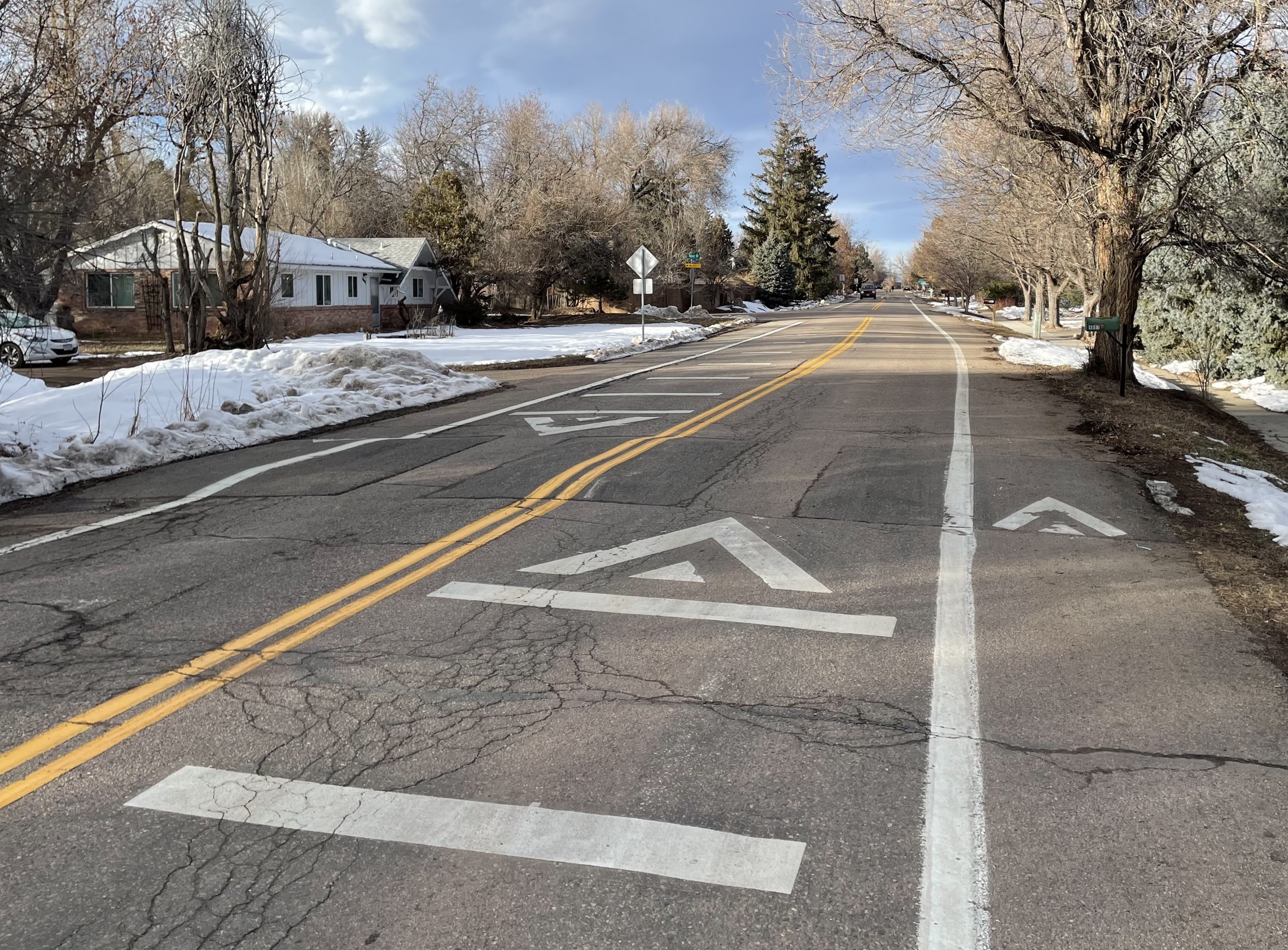 An example speed cushion, or traffic calming device, on 26th Street. It is similar to a speed bump, with raised pavement in the road. It has wheel cutouts for emergency vehicles. It is marked with white paint. 