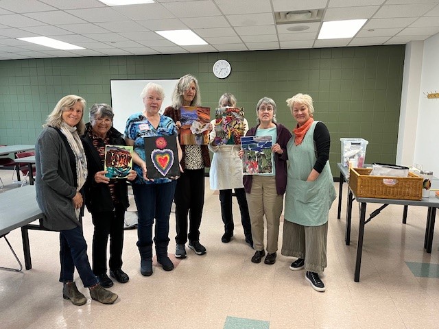 Group of art class participants hold up their artwork