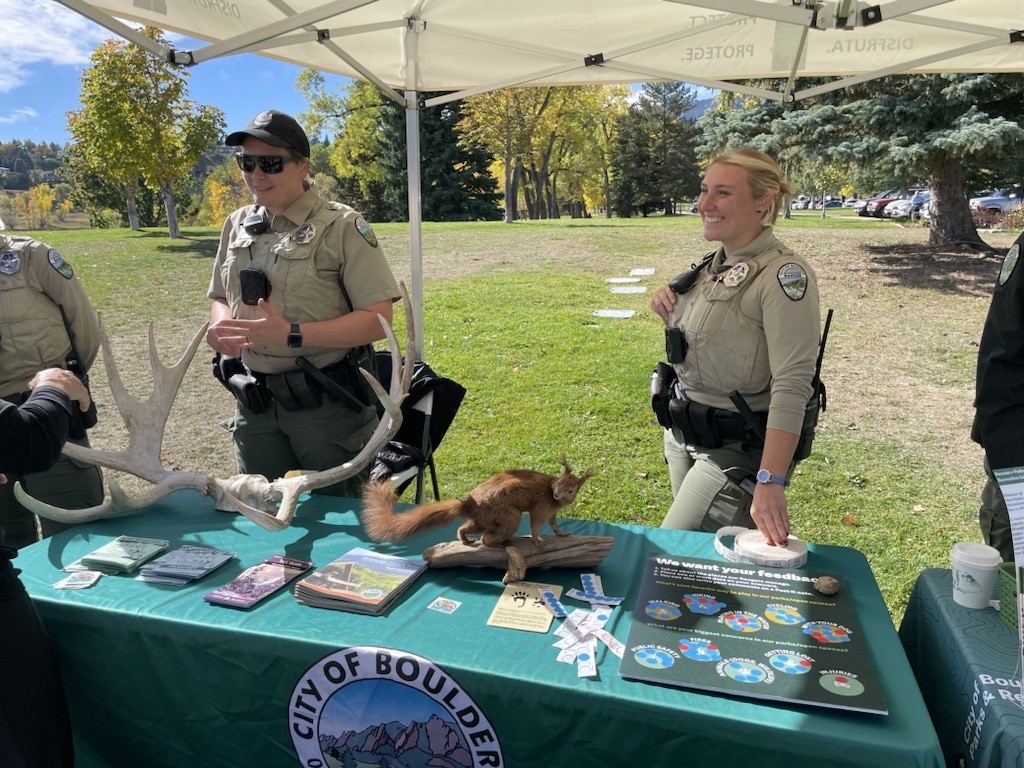 Two rangers and a taxidermized squirrel on table for education program.