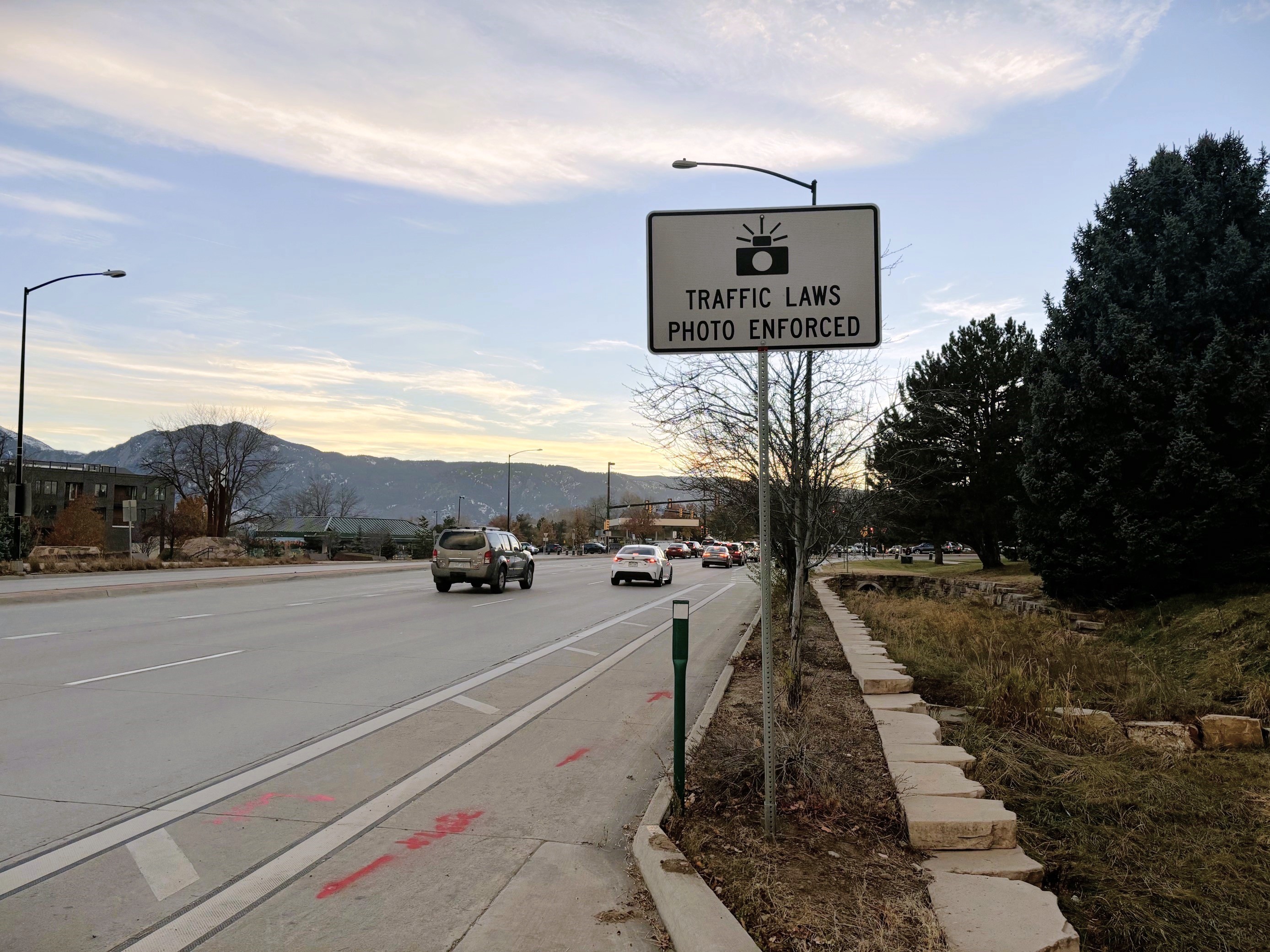 A traffic sign on Iris Avenue. The sign says "Traffic Laws Photo Enforced."