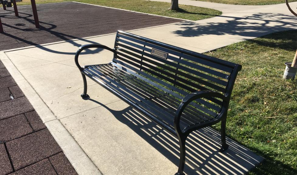 A park bench with a commemorative plaque at foothills playground