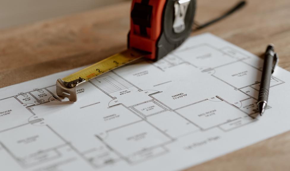 Tape measure with house blueprints and pen