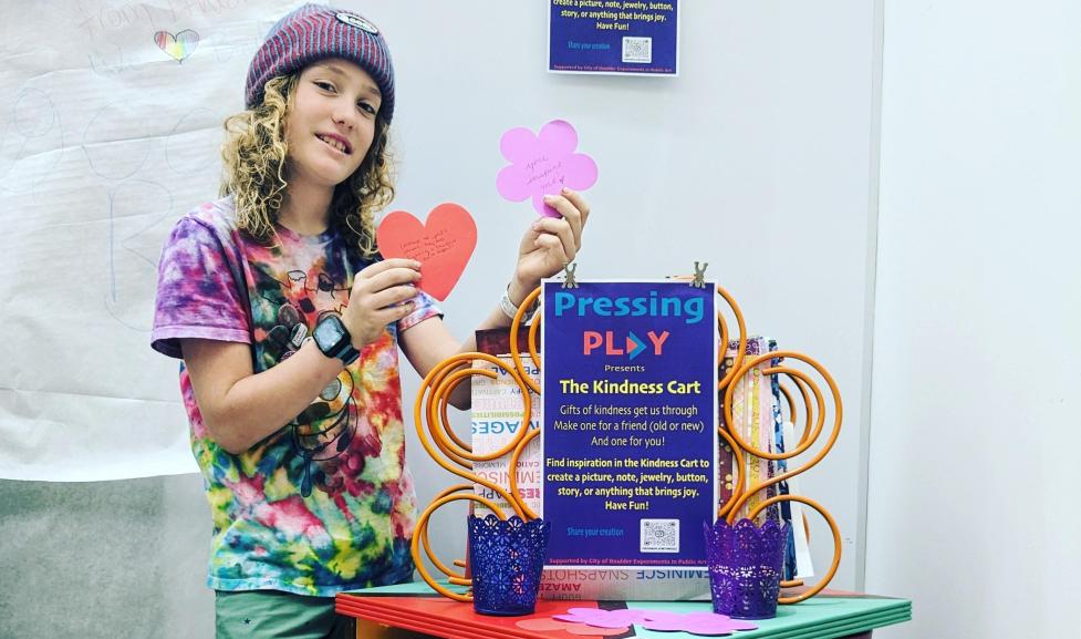 Child interacting with the "Kindness Cart" interactive art piece.