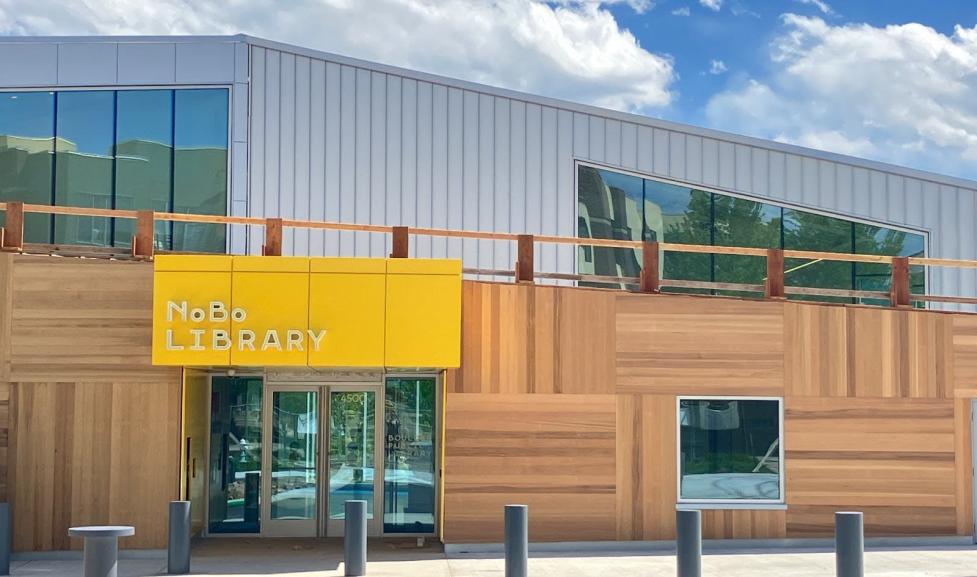 An architecturally unique building with horizontal and vertical wooden face panels and a bright yellow sign.