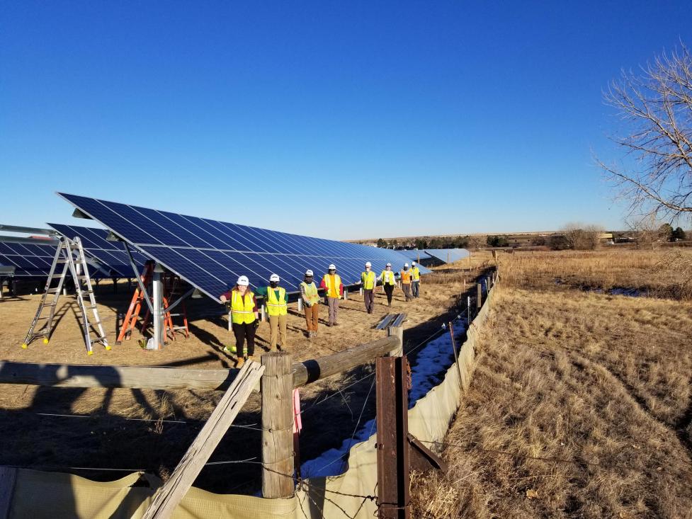 A team of BHP residents in yellow safety vests install a solar garden north of Boulder