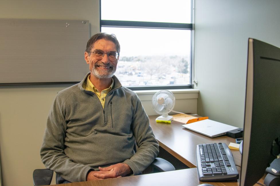 Older man sitting behind a work desk.