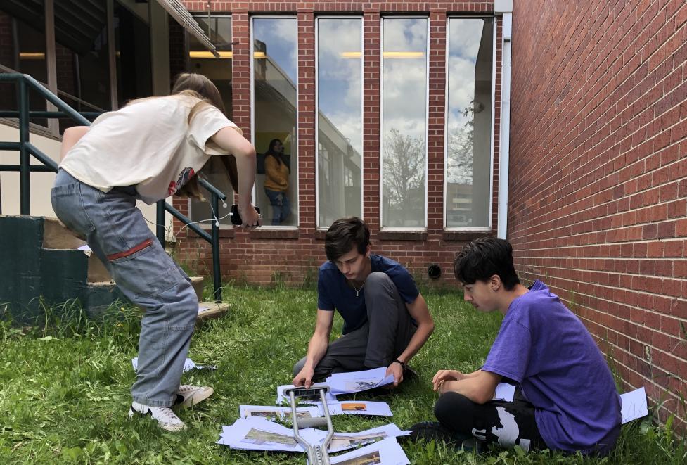 New Vista High School students looking at photos in the grass