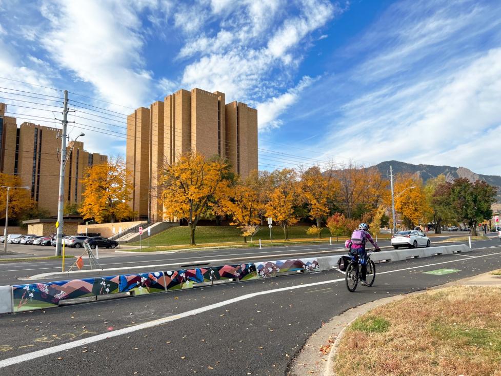 Person biking on Baseline Road near 32nd Street next to tall curbs with art.