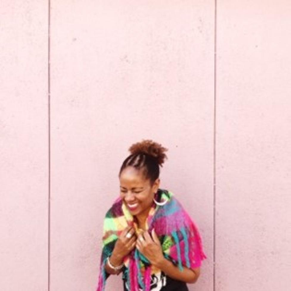 Michele D Simpson laughing and looking down wearing a bright and multicolored shawl. 