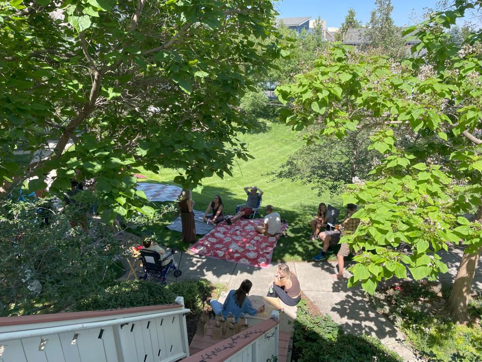 Neighborhood picnic with people sitting on the grass with blankets 