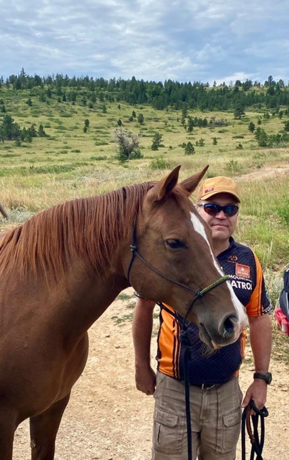 Chuck Anderson, Boulder Mountainbike Patrol volunteer, standing next to a horse