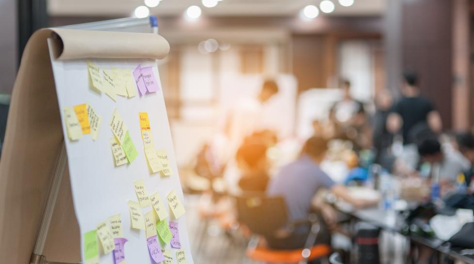 Sticky notes on board with meeting in background