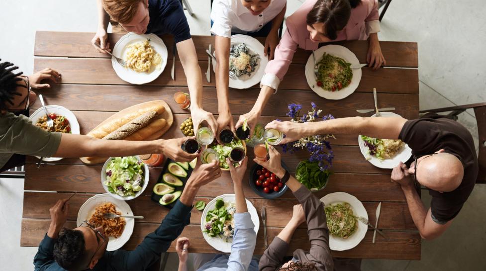 People clinking glasses before having dinner