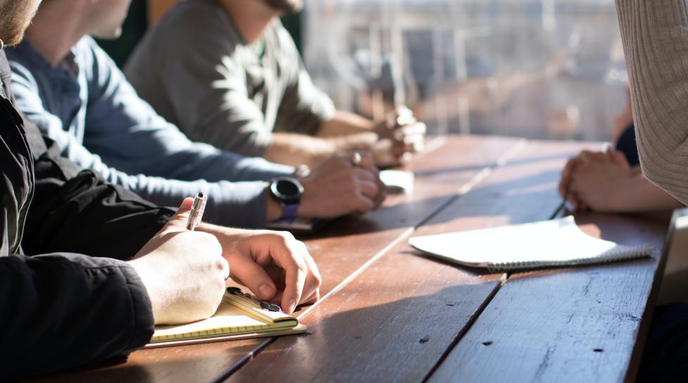 Four people around a table taking notes