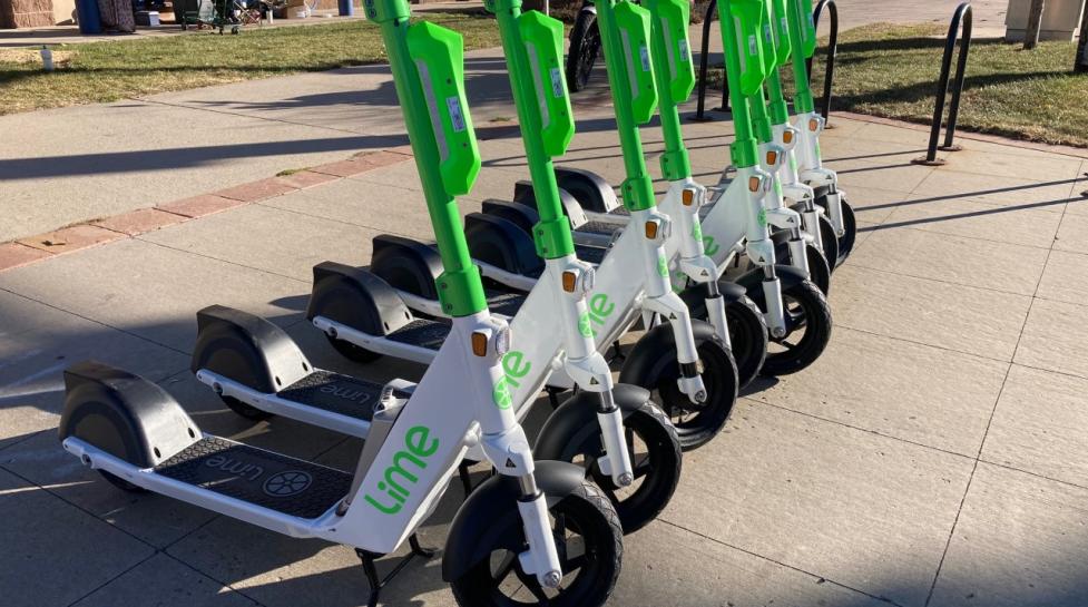 A row of bright green and white electric scooters outside