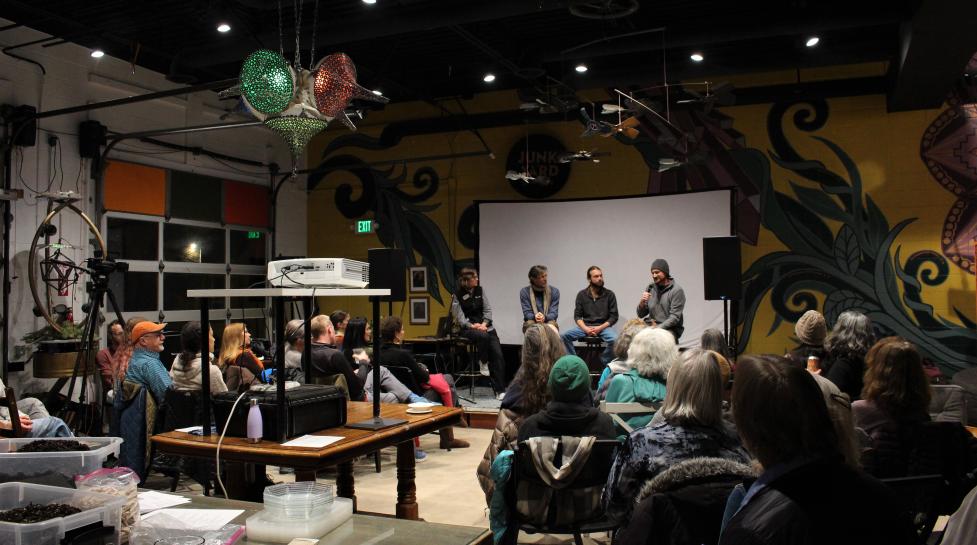 Crowd listens to a panel of local climate leaders talk about innovative projects.