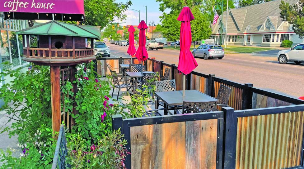 Outdoor dining in front of a coffee shop in the public right away enclosed in a half wall