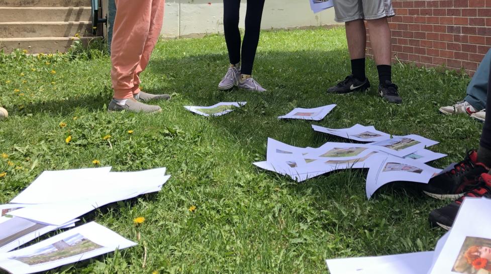 Students standing outside with photos in the grass