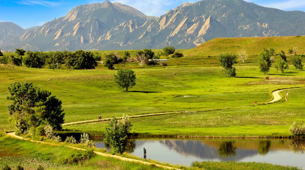 Distant view of the Flatirons and bikers on Open Space