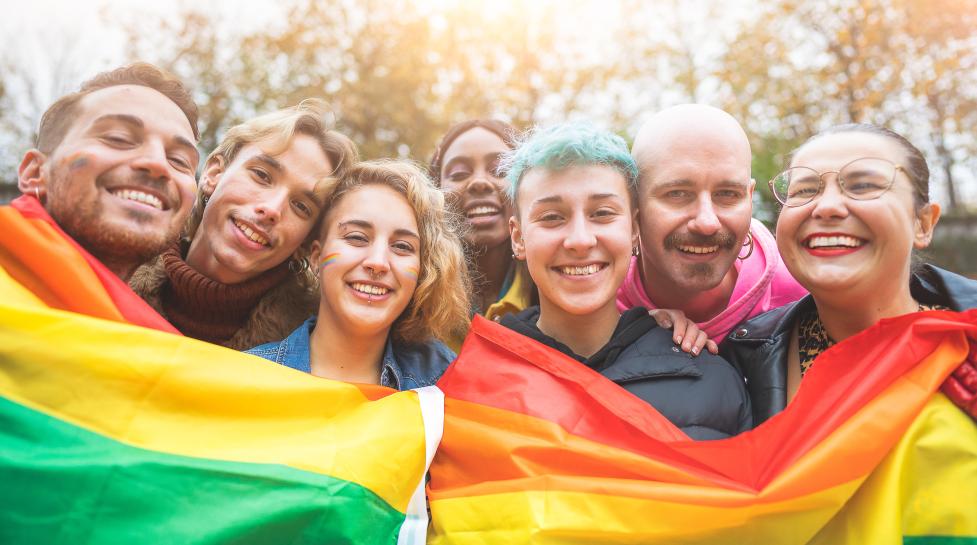 Diverse group of people holding up pride flags