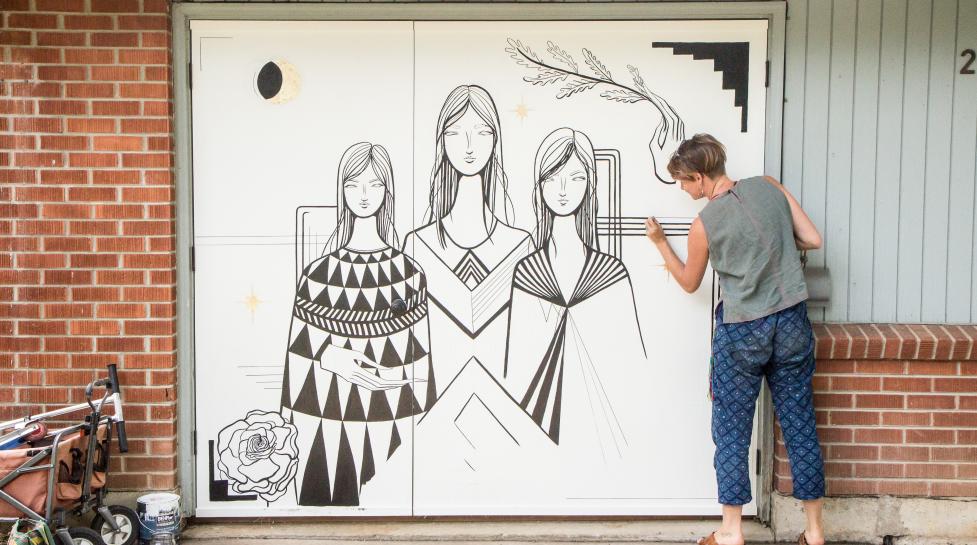 Artist installing mural artwork on a garage door