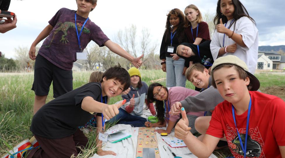 Students giving a thumbs up as they put their thumbprint on a sign for the Nest project