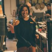 Woman with dark, bobbed hair, black sweater, in a cafe