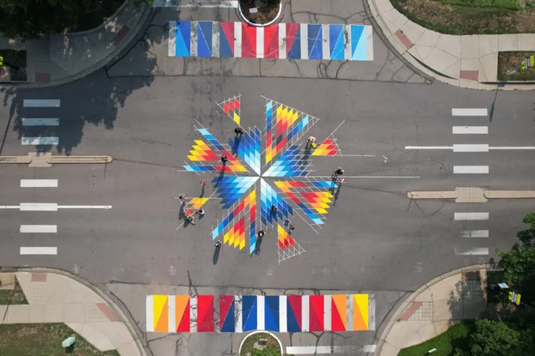 An aerial shot of a colorful and geometric mural on the pavement in the middle of a Boulder intersection