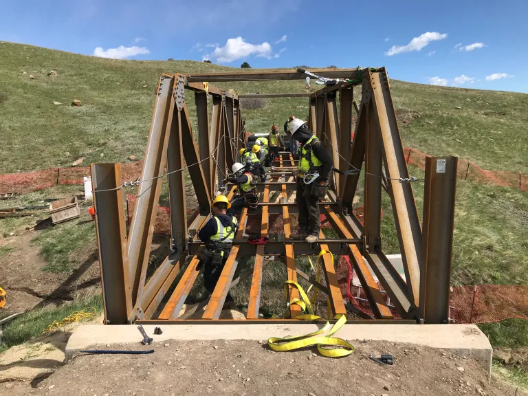 Construction workers laying boards on the deck of the South Bridge on North Sky Trail