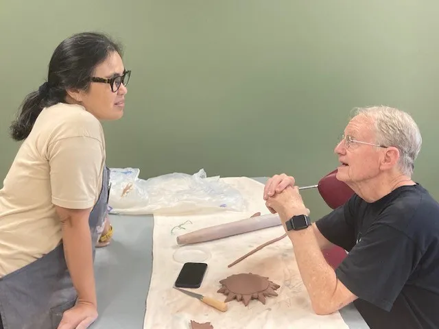 A pottery class participants listens to the instructor's tips on working with clay