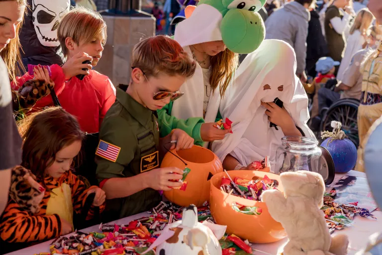 Kids dressed up in costume reaching for candy on a table in downtown Boulder