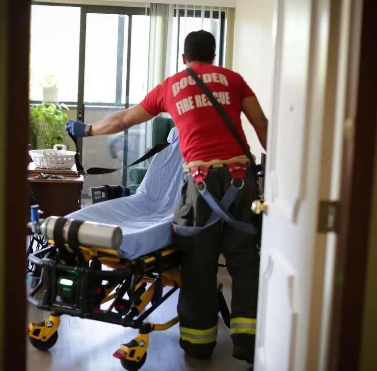 A paramedic prepares a gurney in a hospital room.