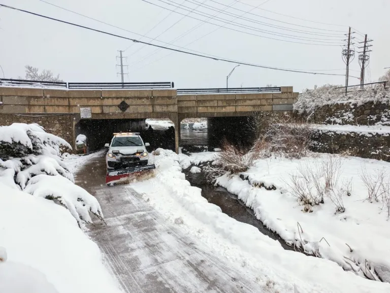 City truck with a plow blade on front clearing snow from a multi-use path.