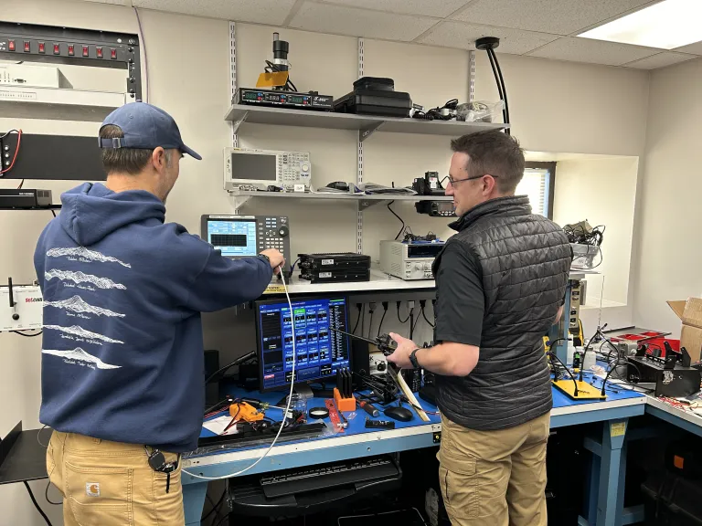 Two city staff members working on a piece of radio equipment to support communications across first responders in Boulder.