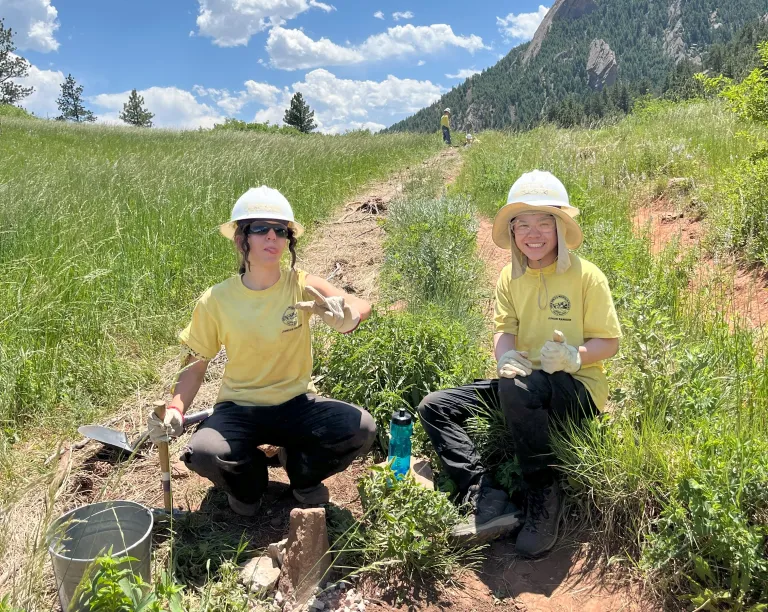 Two junior rangers pose after setting a rock 