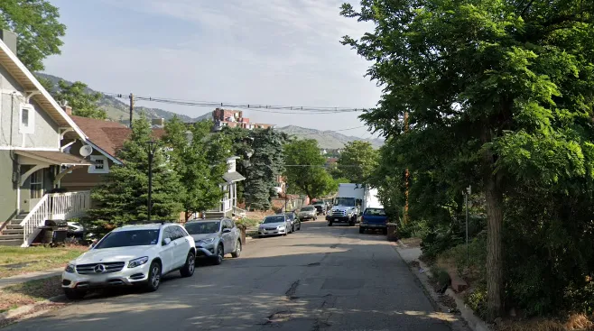 Before photo of Marine Drive without sidewalks. Cars are parked next to the left curb while the right curb is empty. 