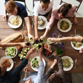 People clinking glasses before having dinner