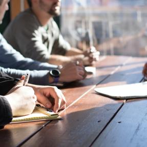 Four people around a table taking notes