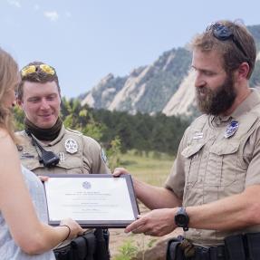 OSMP Rangers give an award to a citizen for helping an injured climber