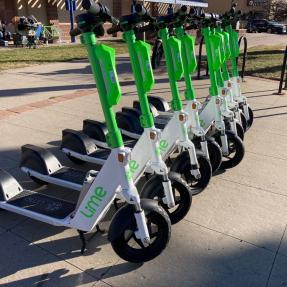 A row of bright green and white electric scooters outside