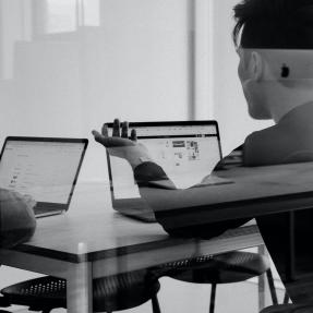 Two people using laptops and having a conversation