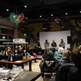 Crowd listens to a panel of local climate leaders talk about innovative projects.