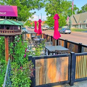 Outdoor dining in front of a coffee shop in the public right away enclosed in a half wall