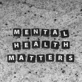 Black letter tiles on a granite background that say "Mental Health Matters"