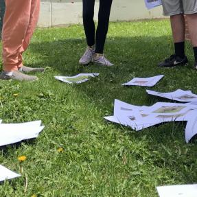 Students standing outside with photos in the grass