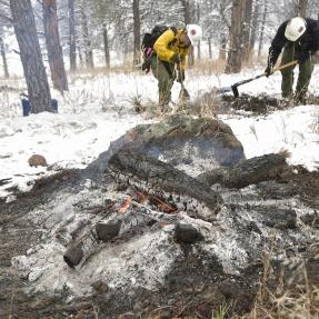 Firefighters monitor the burning of a slash pile