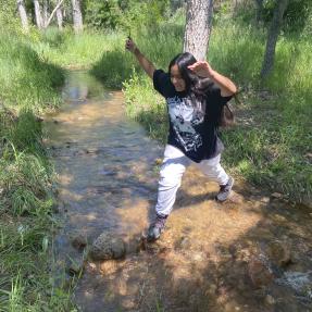 Teenager jumping over the creek at the future park on Violet Avenue